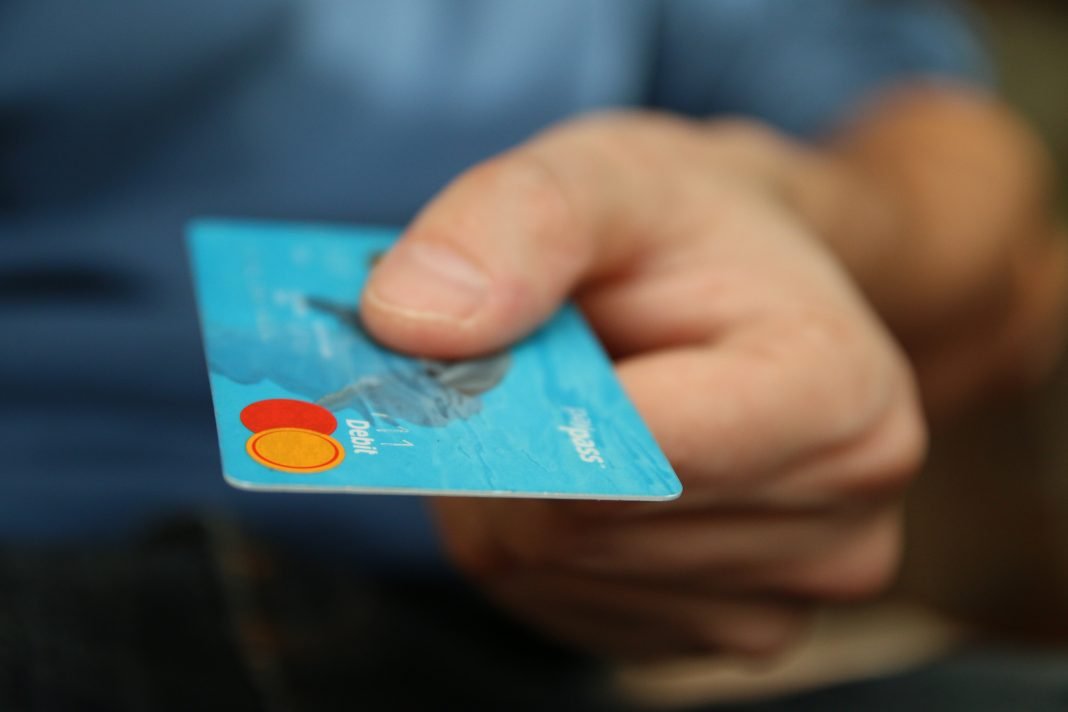 Primer plano de una tarjeta de crédito azul sostenida por una mano