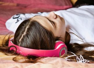 Día Mundial de las tiendas de discos: ¿Qué música escuchan los hackers mientras conducen? Imagen de una chica tumbada escuchando música con unos cascos