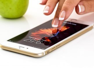 El carnet en el móvil… pero si no eres ‘de la manzana’ Primer plano de un iPhone posado sobre una mesa con unos dedos que tocan su pantalla