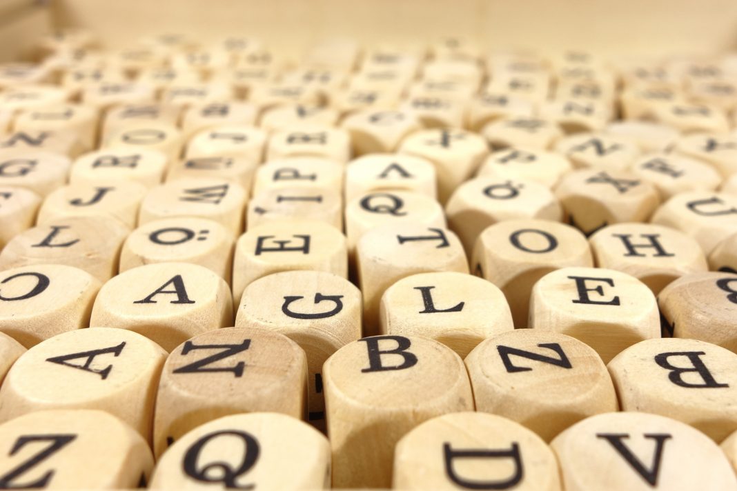 Muchos dados con letras en todas sus caras dispuestos a lo largo de una superficie