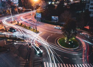 Coches conectados: esto es lo que queda por hacer en cuanto a ciberseguridad Foto de la calle de una ciudad, vista desde arriba, durante la noche y con tráfico pasando