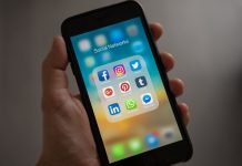Cómo usar las redes sociales de forma segura Primer plano de una mano que sujeta un smartphone. En la pantalla se ven los iconos de acceso a redes sociales como Facebook, LinkedIn, Twitter...
