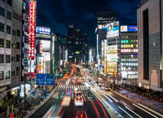 Si tienes coche y este aparatito, en Japón harás cosas increíbles Imagen nocturna de una abarrotada calle de una ciudad japonesa, con carteles de neón y tráfico circulando