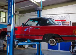 ¿Tendrá tu coche que pasar por el taller este mes? Coche revisión confnamiento: un coche clásico descapotable está subido a una máquina elevadora de taller