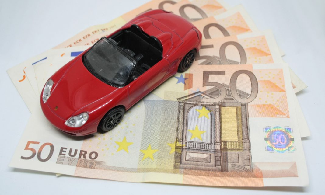 Imagen de un Porsche rojo de juguete colocado encima de unos cuantos billetes de 50 euros