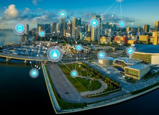 Los retos del vehículo conectado y el 5G: comunicaciones C-V2X Imagen de una ciudad con varias señales de conexión uniendo diversos puntos de la misma