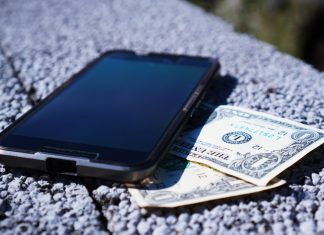 «Casi todos los ciberataques se producen por dinero» Imagen de un teléfono móvil apoyado encima de un muro con varios billetes bajo él